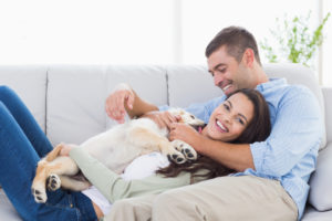 happy couple relaxing on sofa with puppy