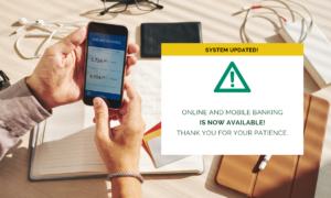 A pair of hands holding a phone with online banking on it, with a text box that reads: System Updated! Online and Mobile Banking is now available! Thank you for your patience.